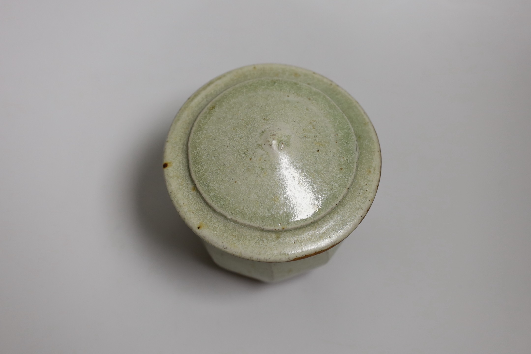 Richard Batterham (1936 – 2021), a cut sided stoneware jar and pointed cover with sage coloured glaze. 10.5cm high